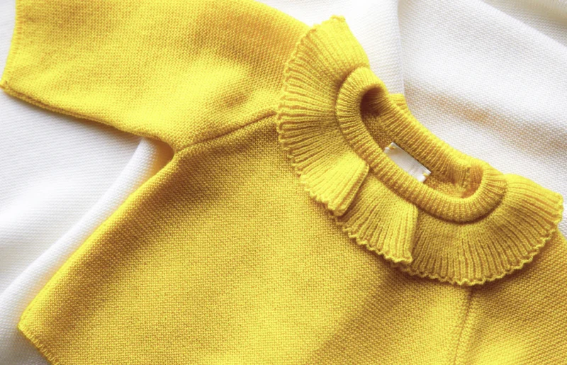 Close-up of yellow knitwear piece from Molli, a chic Parisian-loved brand for babies.