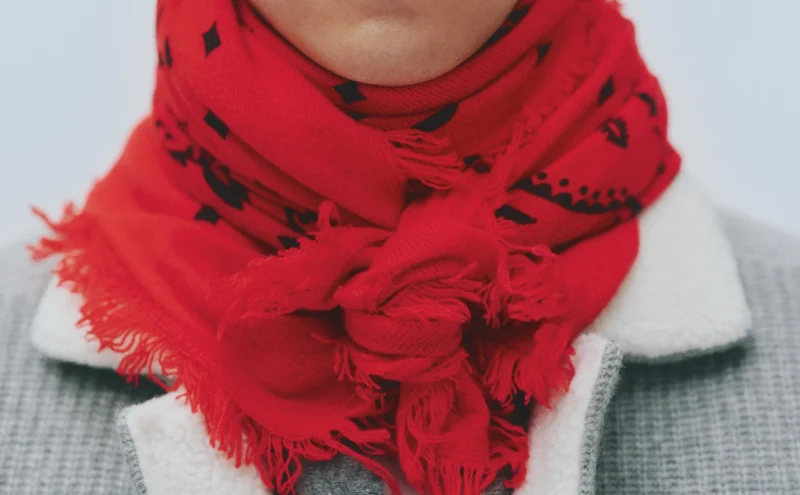 Close-up of a French scarf by Kujten, red wool bandana scarf knotted at the neck.
