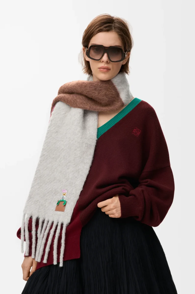 Model wearing a French scarf by Loewe, oversized grey and brown mohair scarf with fringe, styled over a burgundy sweater.