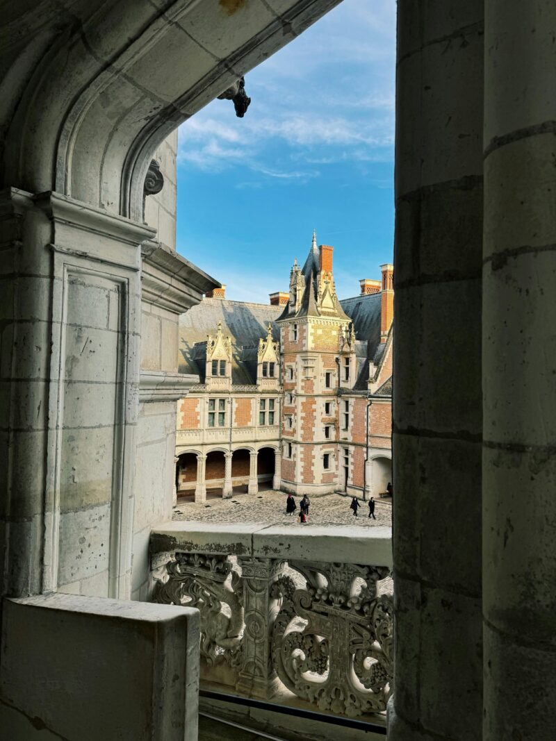 Château de Blois, a historic castle in the Loire Valley France, seen through an arched window.