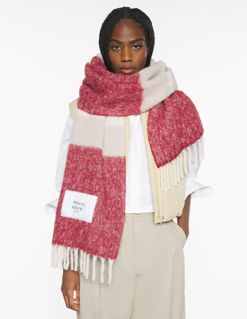 Close-up of red mohair French scarf by Maison Kitsuné, knotted at the neck with fringed edges.