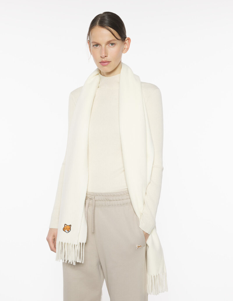 Model wearing a white French scarf by Maison Kitsuné with fringed edges and fox logo.