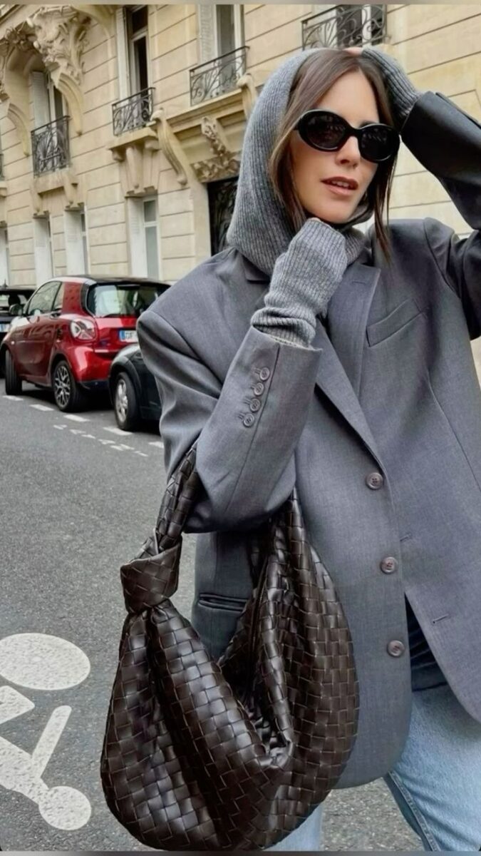 Woman in oversized grey blazer with a brown woven hobo handbag on the streets of Paris.