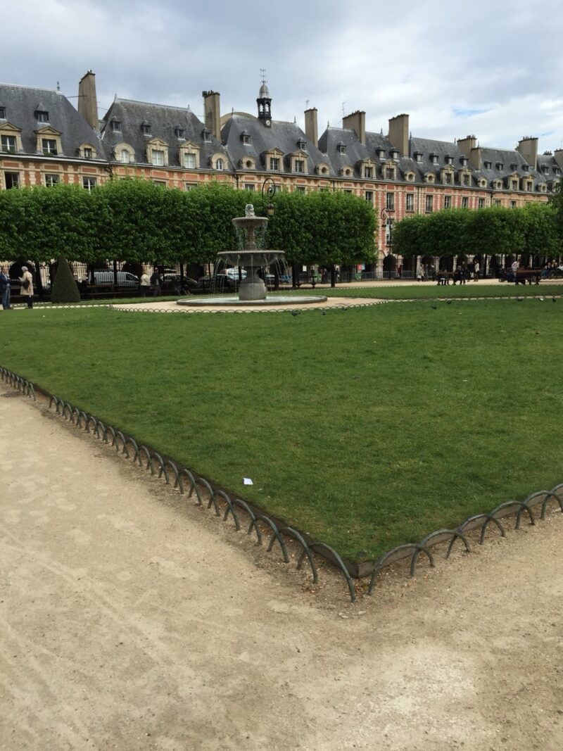 Families relaxing on the grass at Place des Vosges, Paris