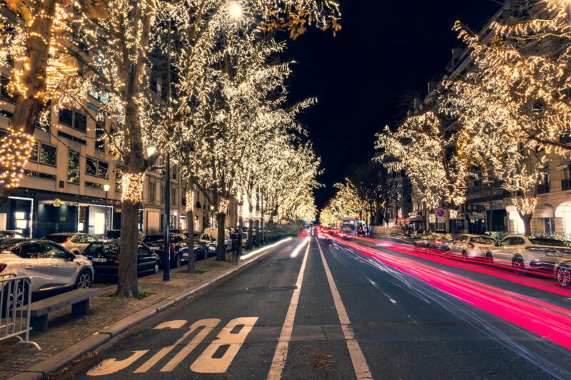 A Paris street illuminated with golden Christmas lights.