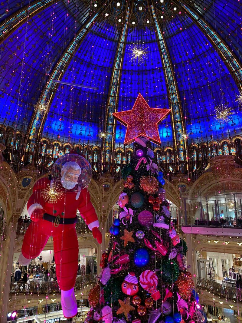 Giant Christmas tree and Santa Claus decoration under the Galeries Lafayette dome in Paris during the holidays.