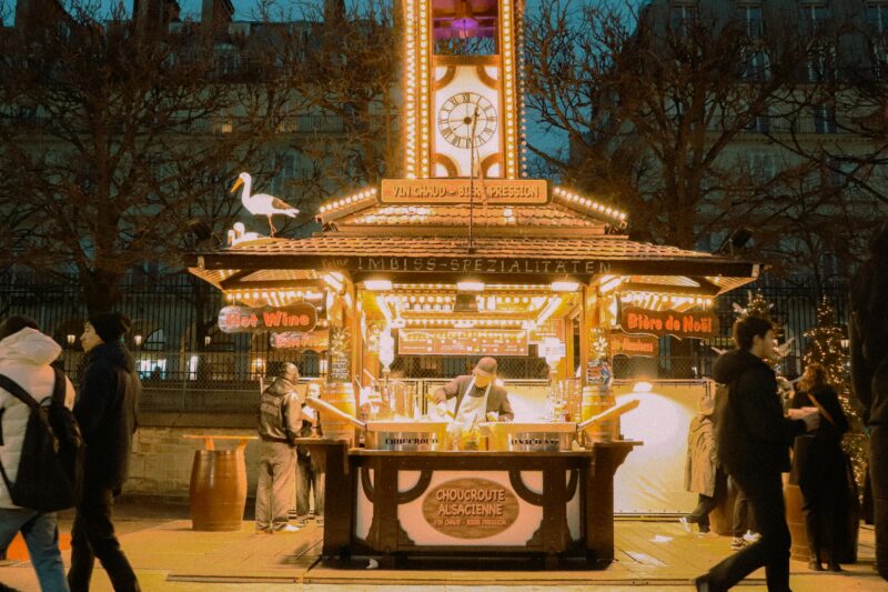 Wooden chalet stall at a Paris Christmas market in Tuileries selling vin chaud and Alsatian specialties.