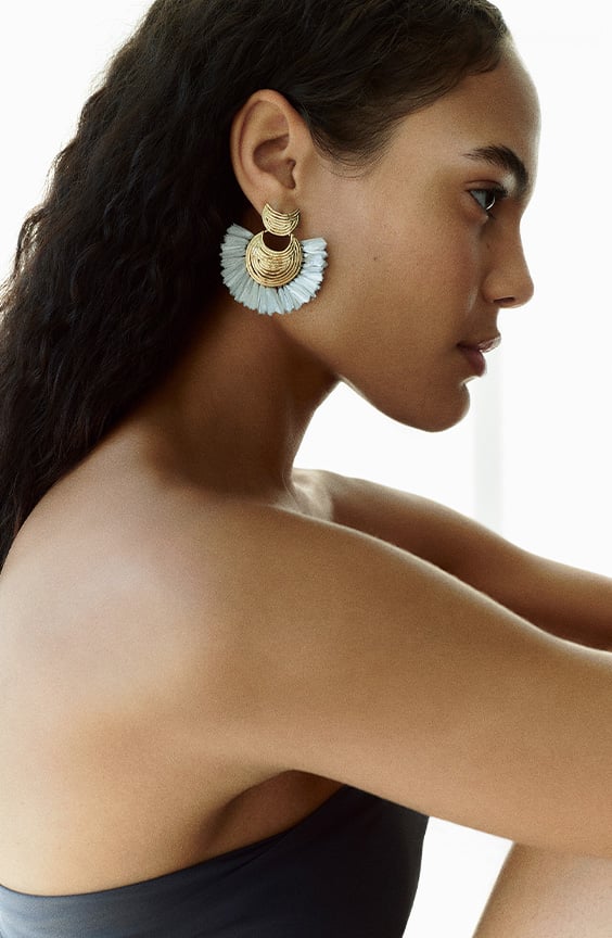 Woman wearing gold statement earrings by Gas Bijoux Paris