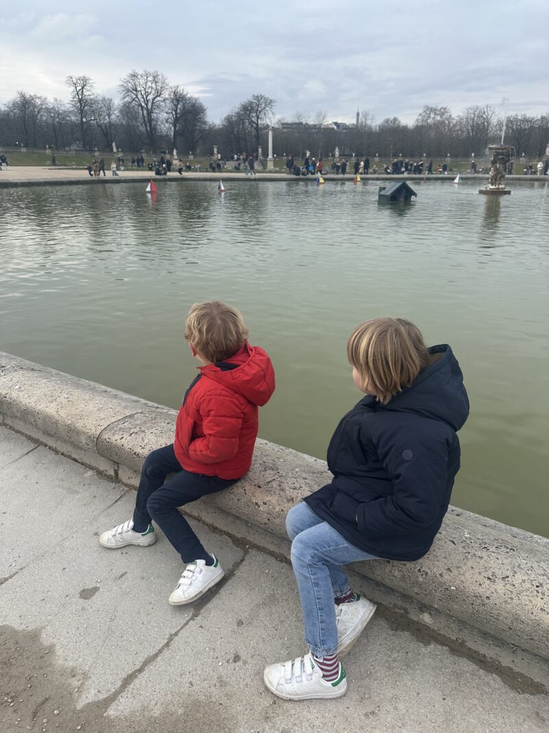 children watching sailboats on the pond at Jardin du Luxembourg in Paris during winter
