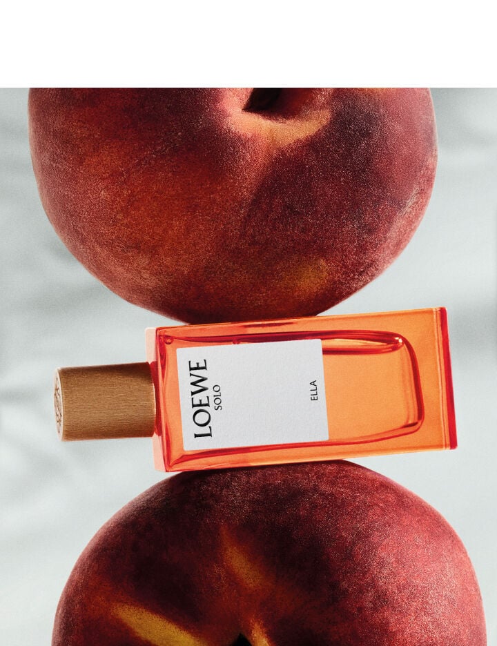 Loewe 001 Woman perfume bottle styled with peaches