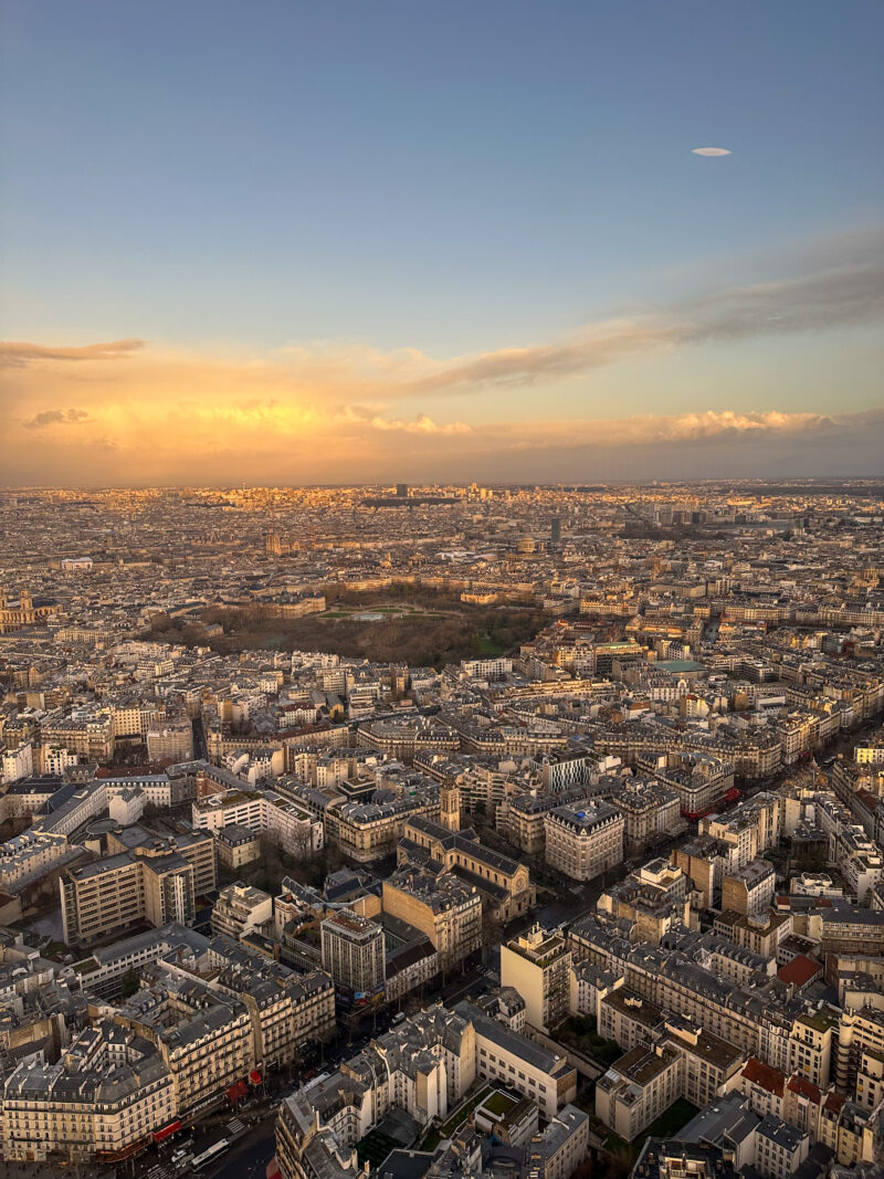 Aerial view of Paris rooftops and the Eiffel Tower at sunset in December.