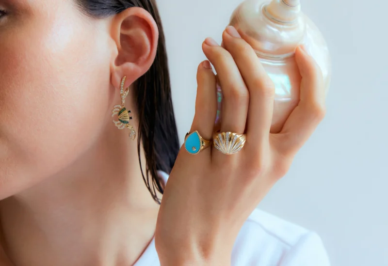 Close-up of gold earrings with pearls and charms by Yvonne Léon, Parisian jewelry designer.