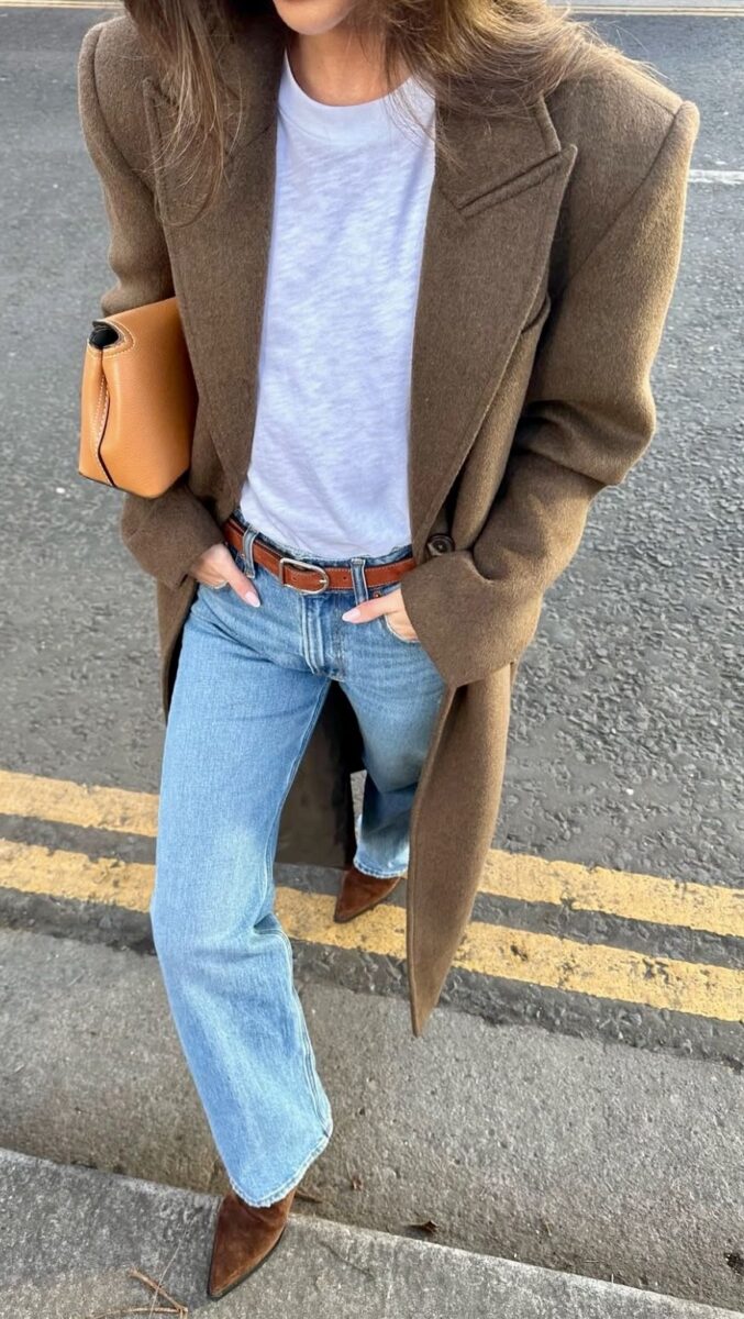Woman wearing a brown wool coat, white tee, and straight-leg jeans — a chic example of what to wear in Paris in winter.